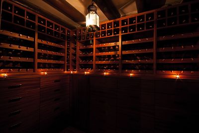 Bodega de vino en una casa particualr hecho con madera y con una lámpara colgando en medio de la sala.